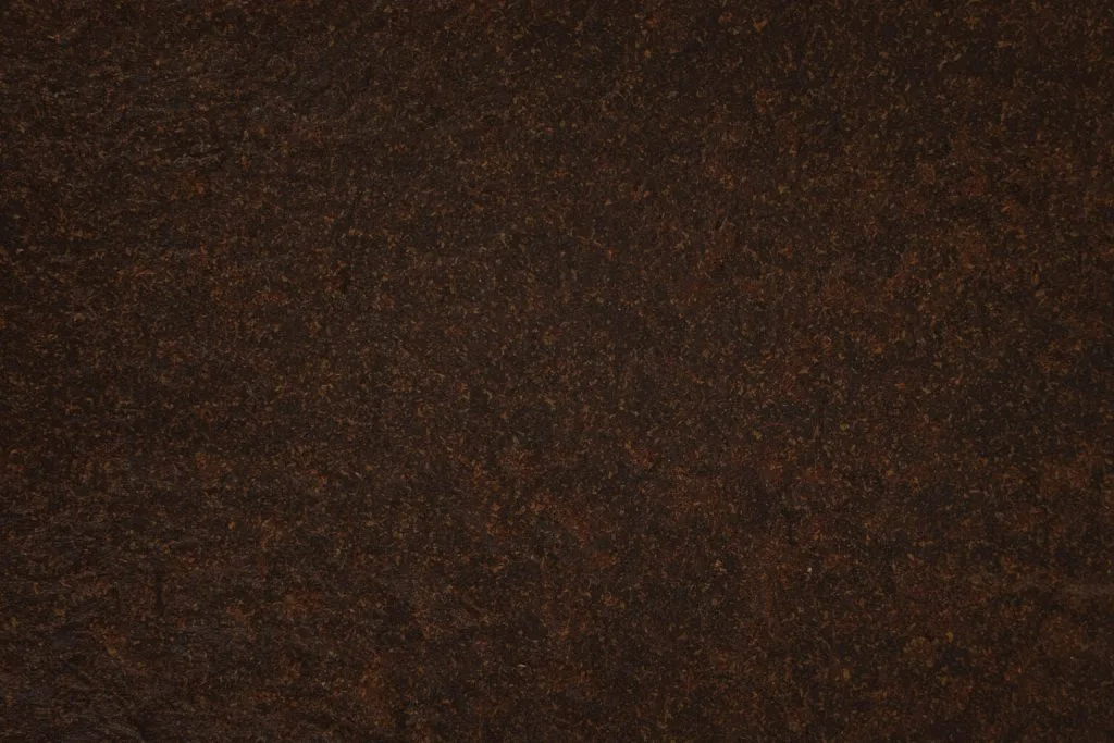 Close-up of dark brown, textured, rust-colored metal surface with speckled pattern