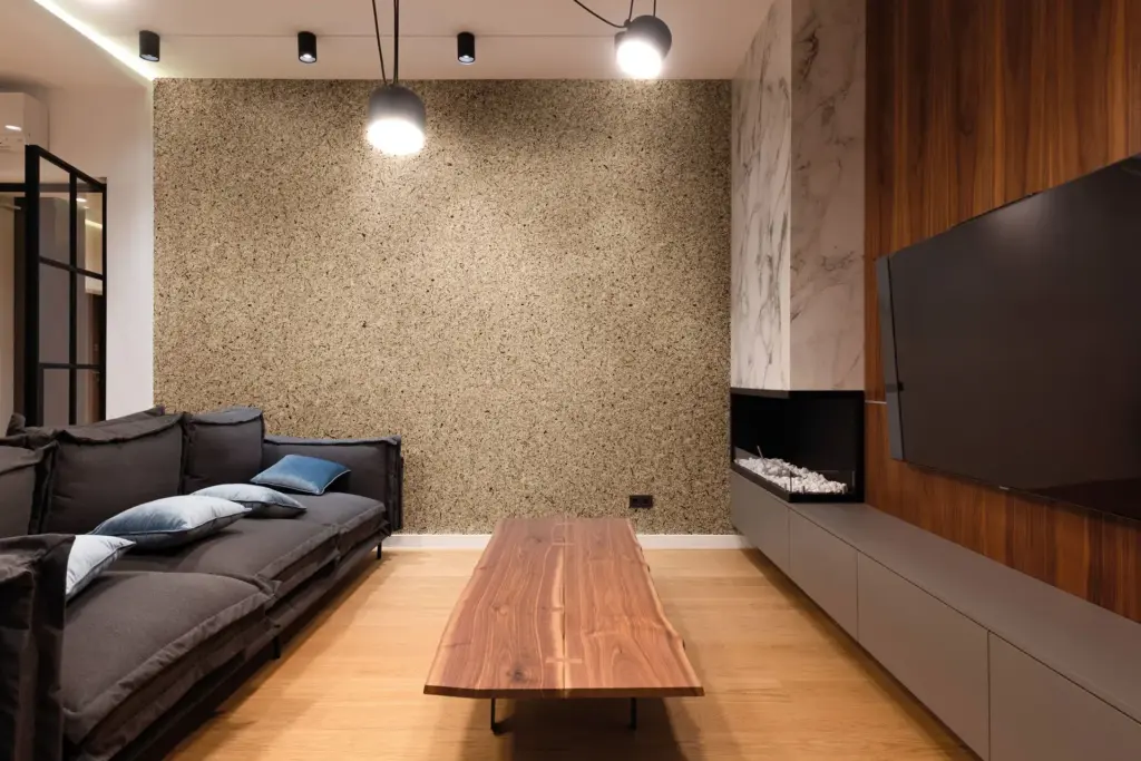 Innenaufnahme eines modernen Wohnzimmers mit Sofa, Holz-Tisch, Kamin und TV an einer Wand