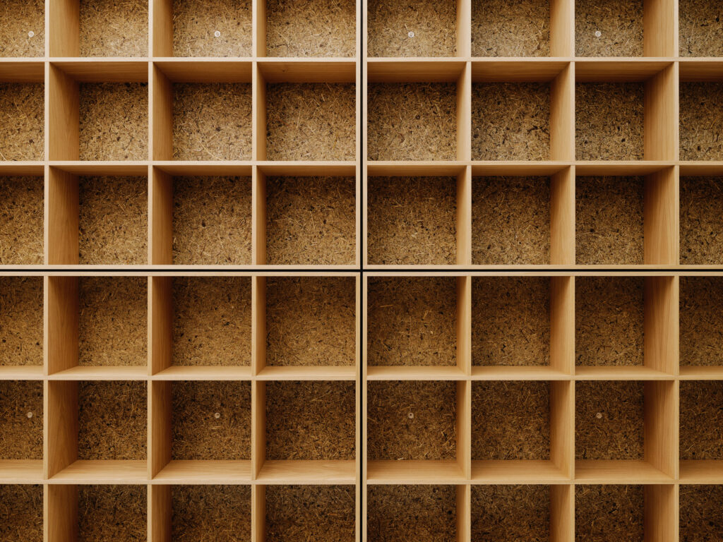 Empty wooden cubby shelves with a cork backing, arranged in a grid pattern