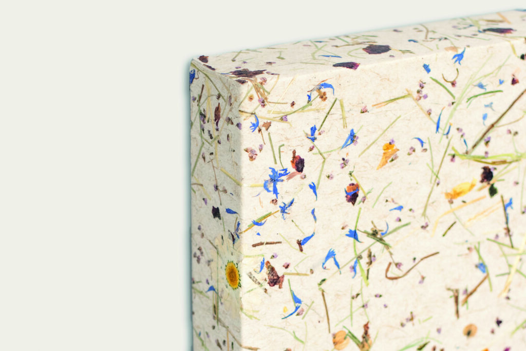 Verpackung aus biologisch abbaubarem Material mit getrockneten Blumen und Pflanzenmotiven