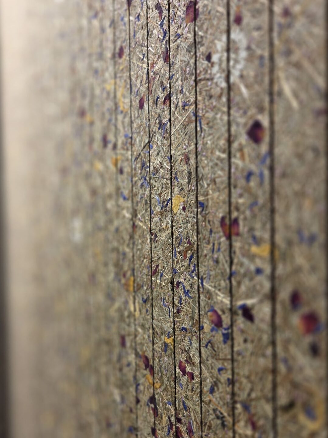 Bodenbelag mit Holzspänen und getrockneten Blüten in verschiedenen Farben, vertikal ausgerichtet