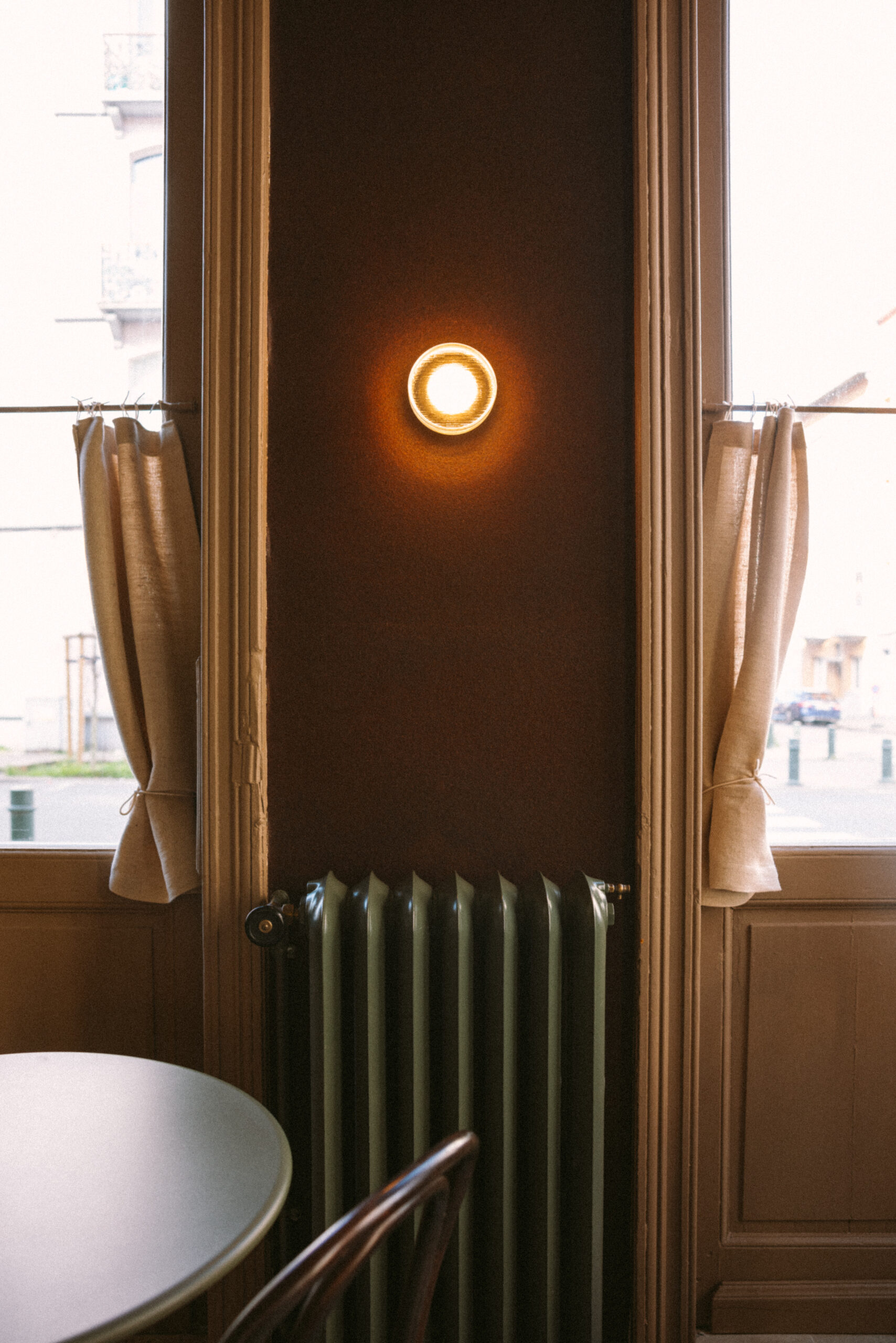 Ein Fenster mit Vorhängen, eine Heizung und eine beleuchtete Wandlampe in einem Raum