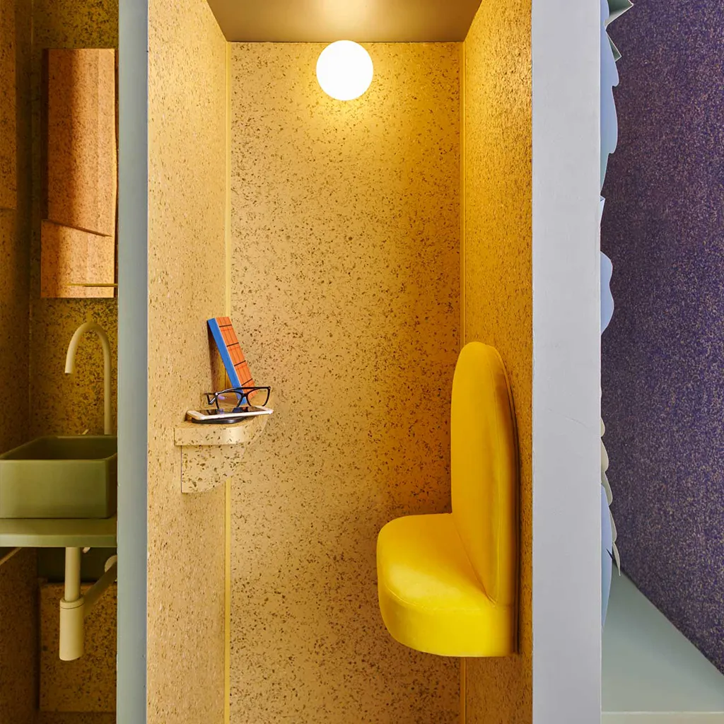 Eine Büro Ecke mit einer Sitzmöglichkeit und einer goldenen Wand mit Blättern. 