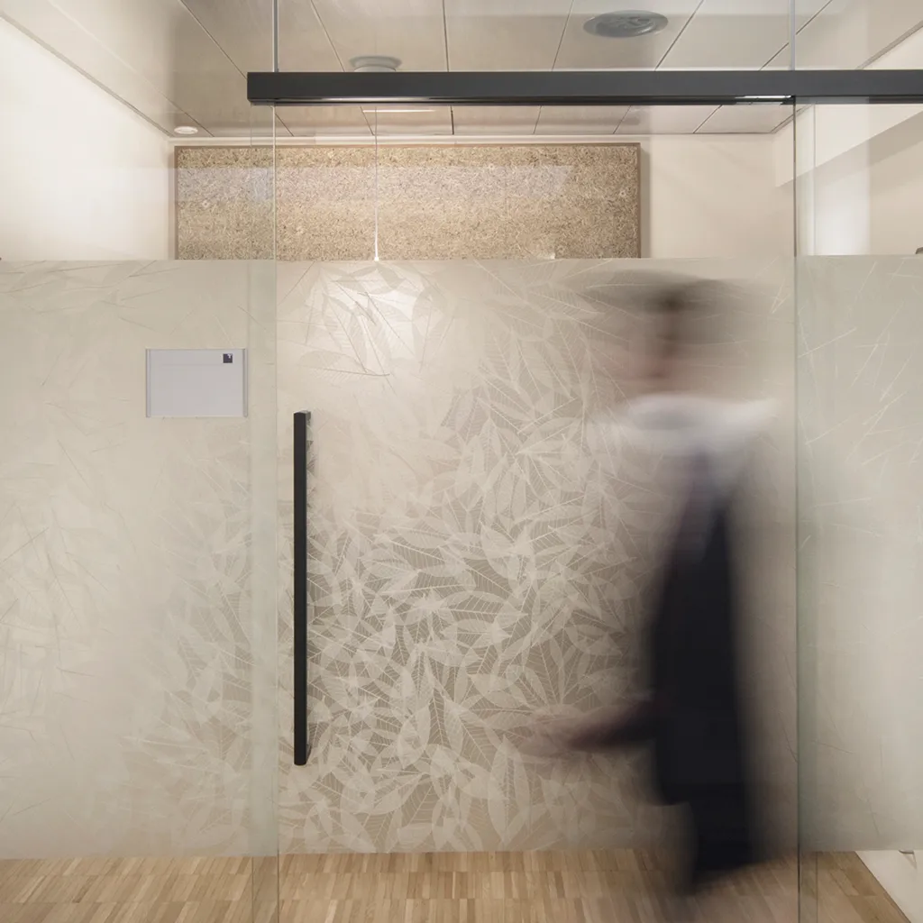 Blurry Person geht durch eine Glas-Tür mit echten Blättern als Sichtschutz, halbdurchsichtig, im Bürogebäude 