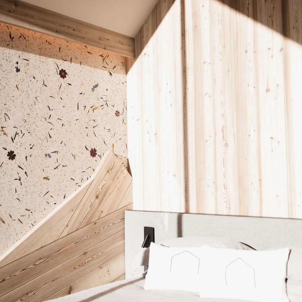Bett mit weißen Kissen vor Holzvertäfelung und Wand mit Blumenmuster