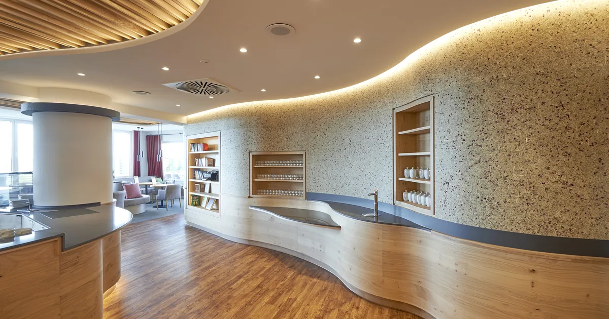 Moderne, helle Lounge mit geschwungener Holzbar, Bücherregalen und Sitzbereich