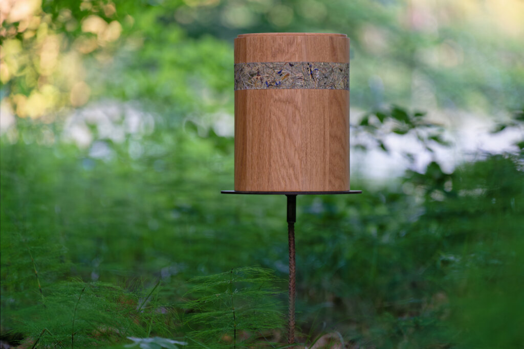 Ein runder Holz-Container mit einer dekorativen Schicht aus Naturmaterialien auf einem schwarze...