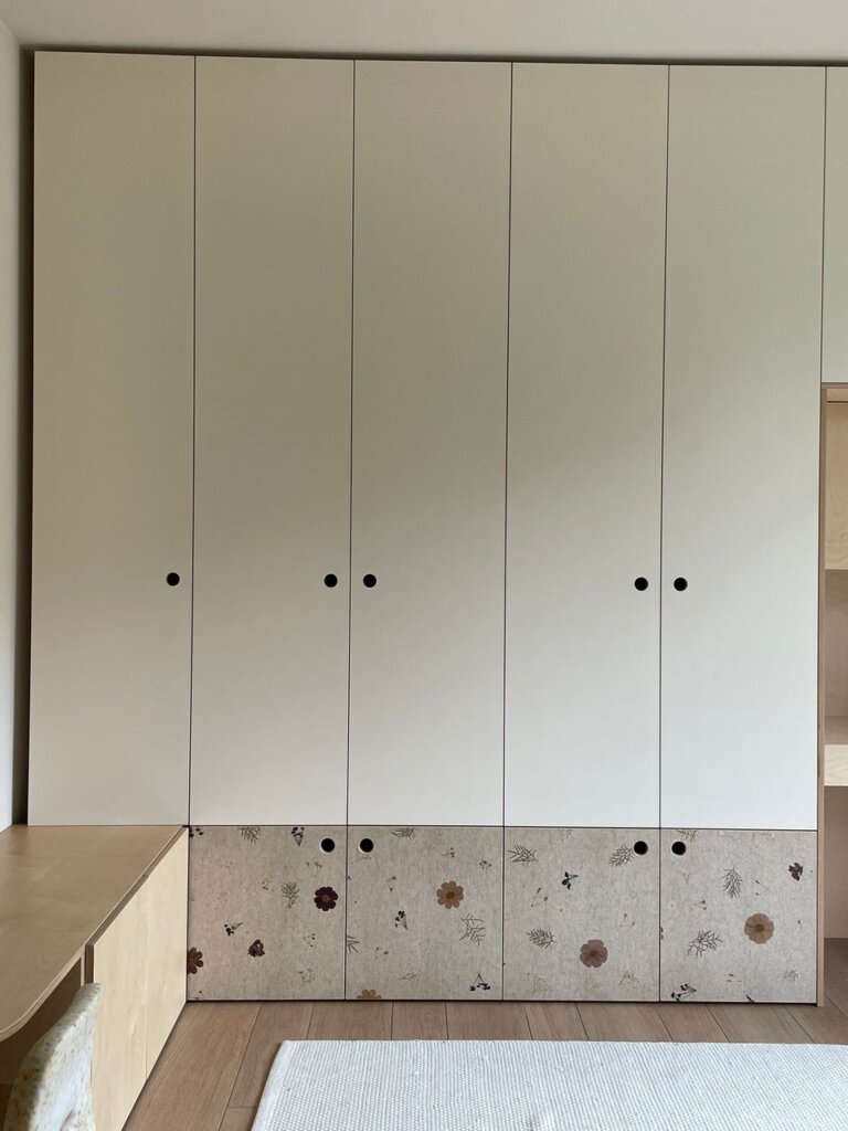 Schrank mit weißen Türen und einer unteren Reihe mit floral gestalteten Türen in Holzoptik