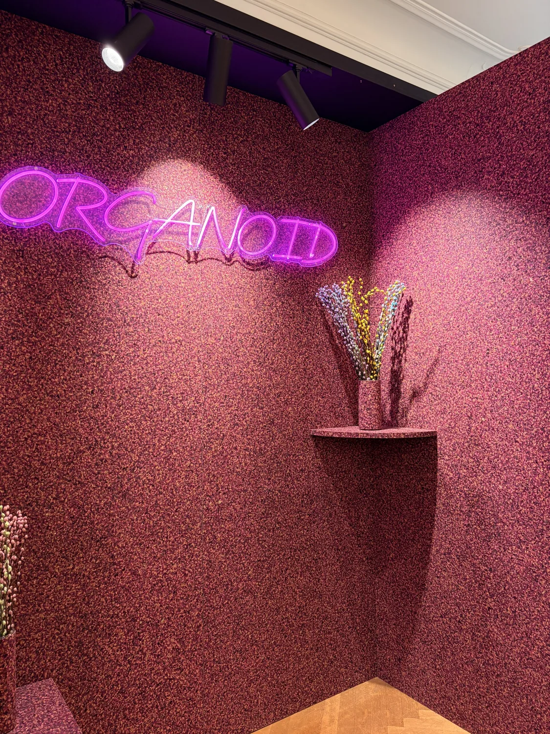 Messestand von ORGANOID auf der ORGATEC mit pinker Naturoberfläche und Neon-Schriftzug
